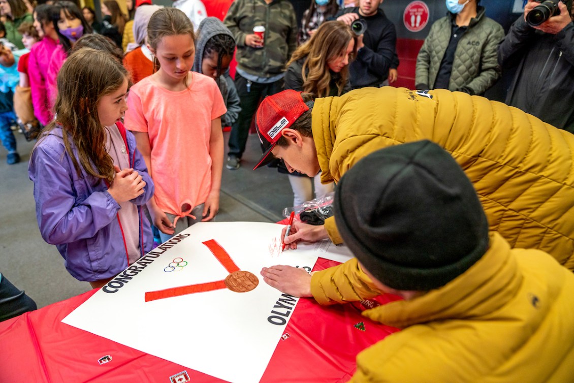 Deux hommes signent des autographes à des enfants.