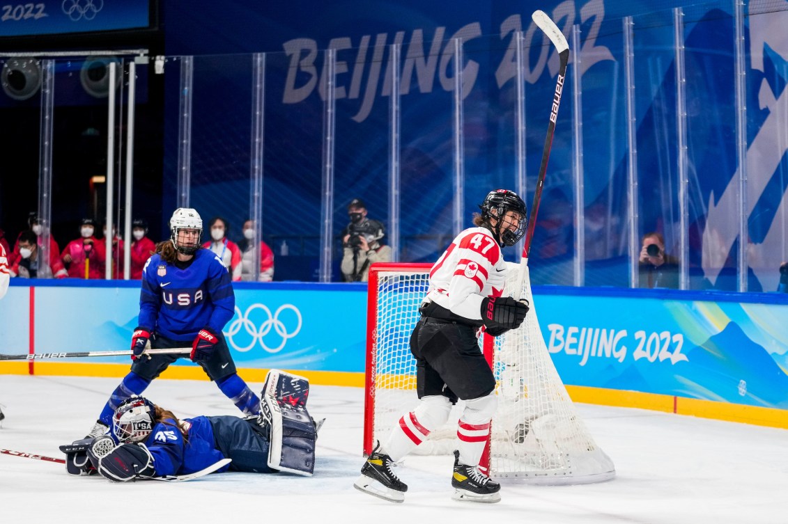 Une joueuse devant un filet de hockey. 