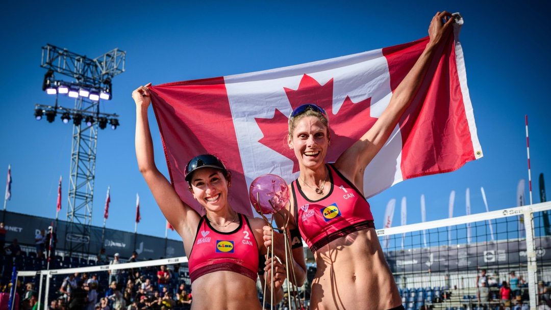 Deux joueuses de volleyball de plage tiennent un drapeau canadien.