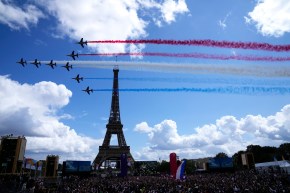 Des avions de chasse tracent des lignes bleues, blanches et rouges dans le ciel devant la tour Eiffel.