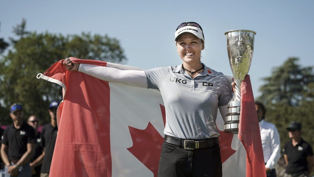 Brooke Henderson avec un trophée et le drapeau canadien.