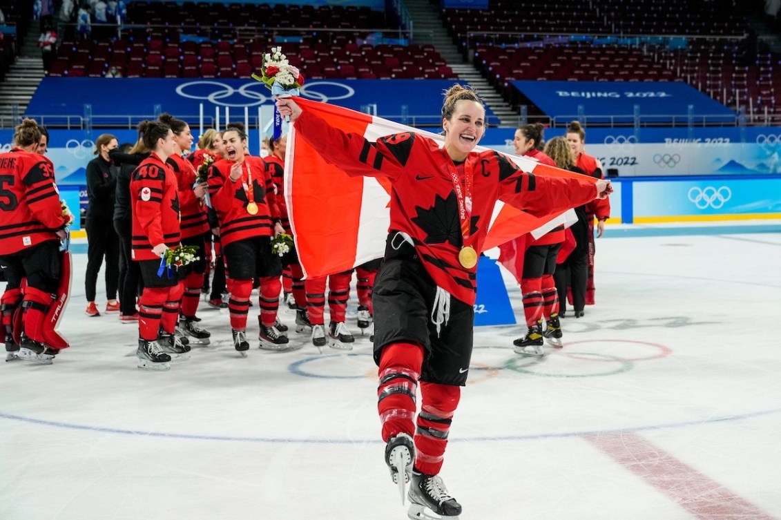 Marie-Philip Poulin tient le drapeau du Canada à bout de bras. 