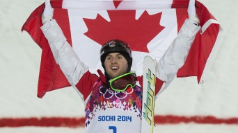 Alexandre Bilodeau lève les bras dans les airs.