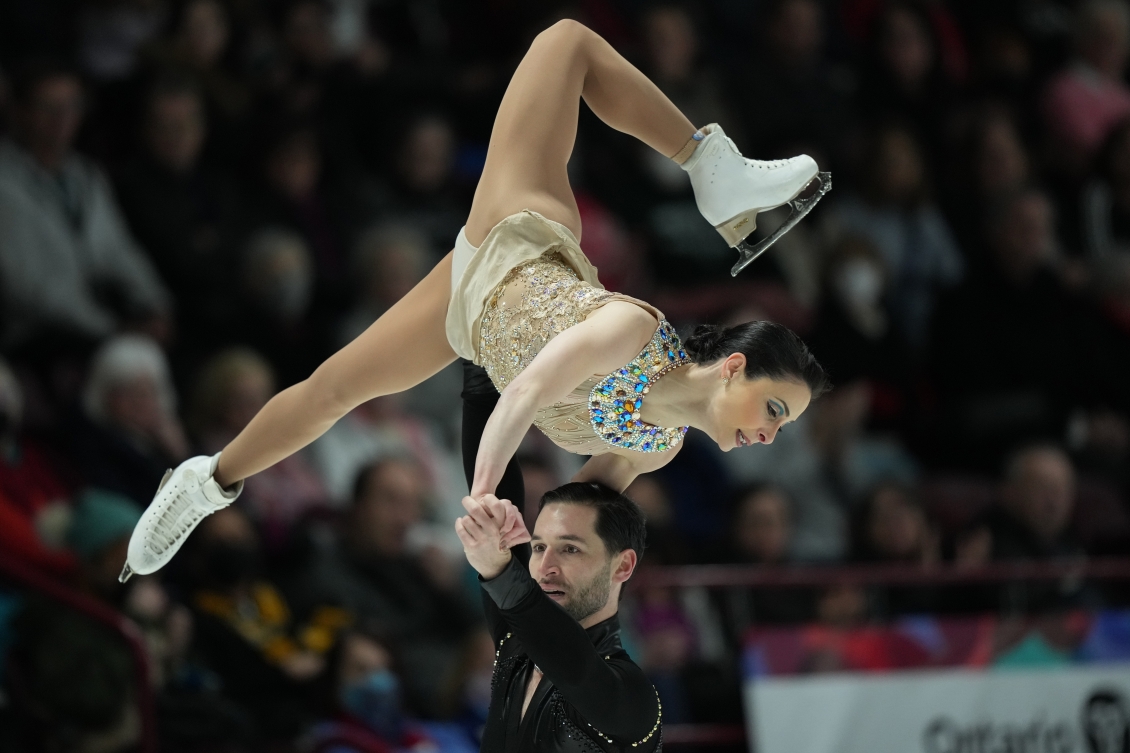 Un patineur soulève sa partenaire dans un portée. 