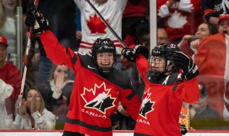 Deux joueuses canadiennes de hockey les bras dans les airs.