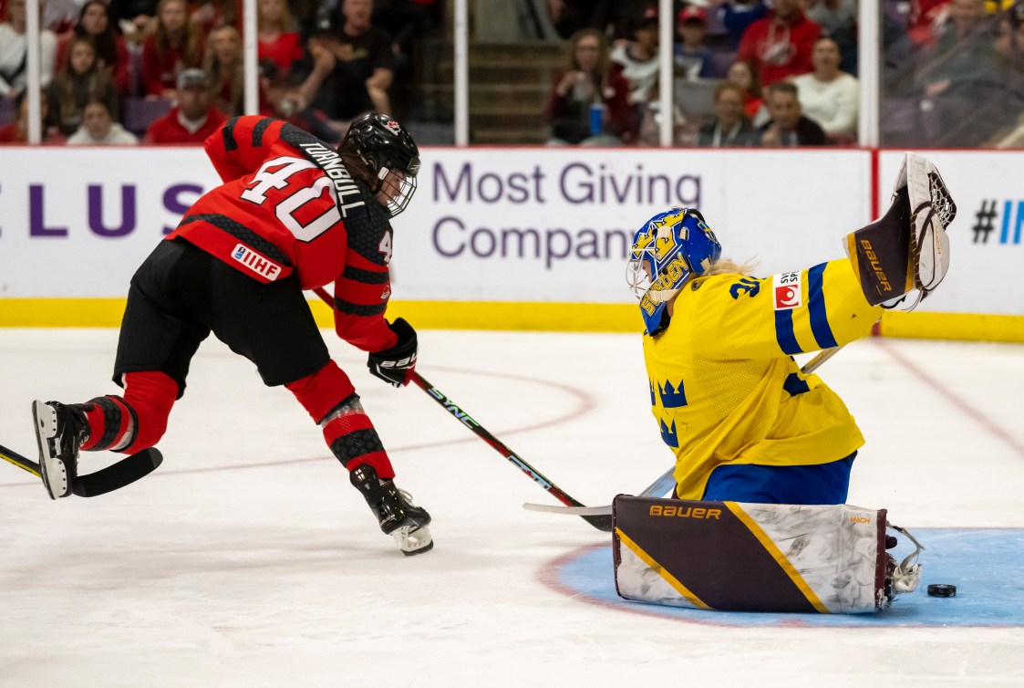 Une joueuse canadienne marque devant une gardienne de but suédoise. 