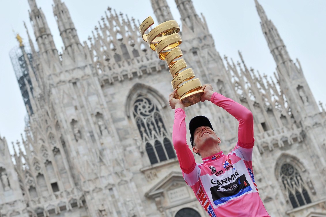 Un cycliste tient un trophée.