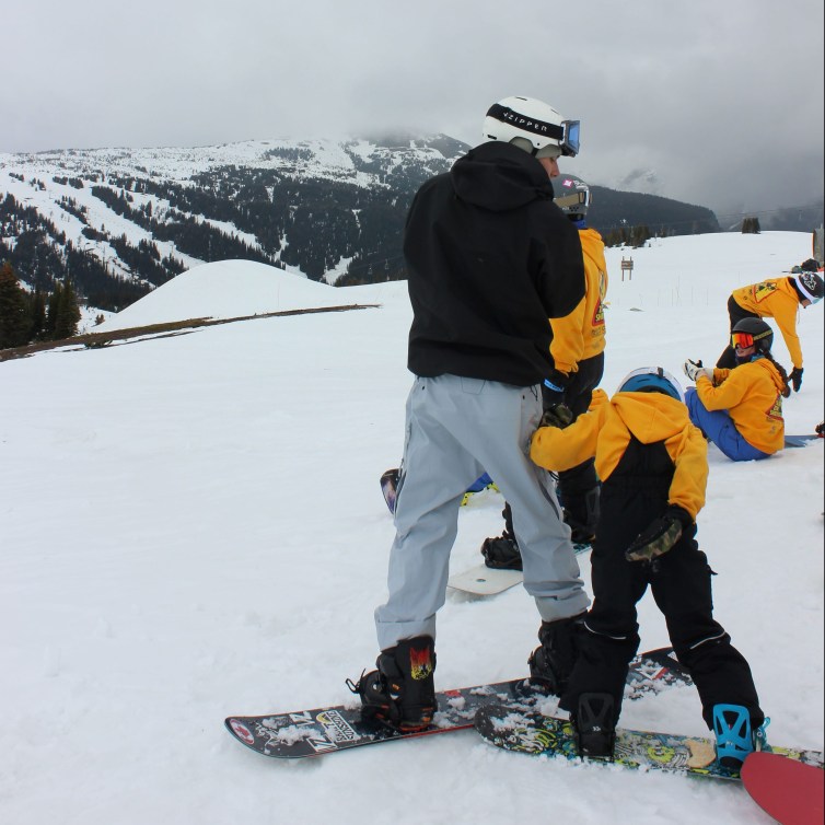 Liam Gill aide un jeune snowboarder autochtone.