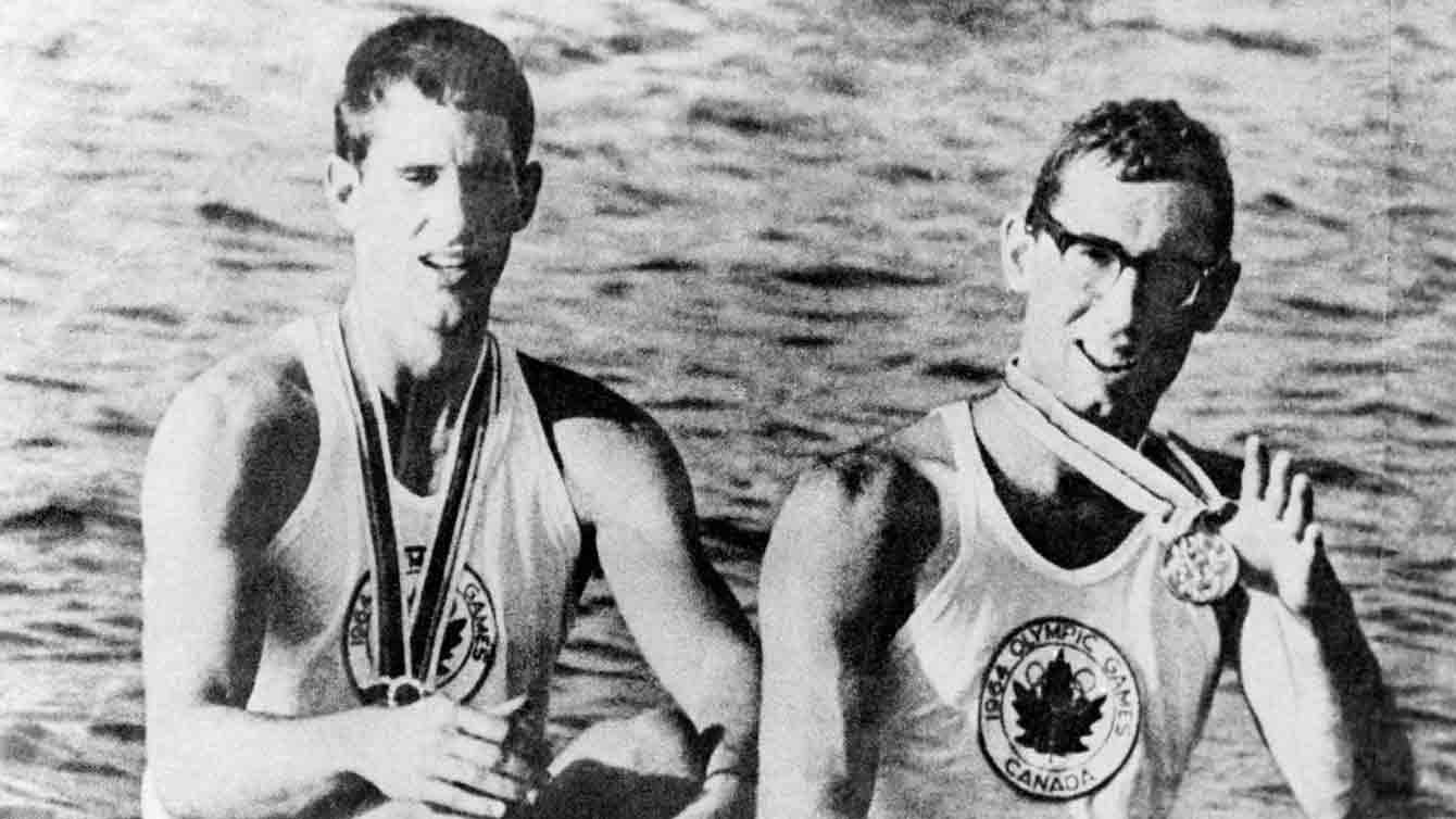 Photo en noir et blanc de deux hommes dans une embarcation avec des médailles au cou.