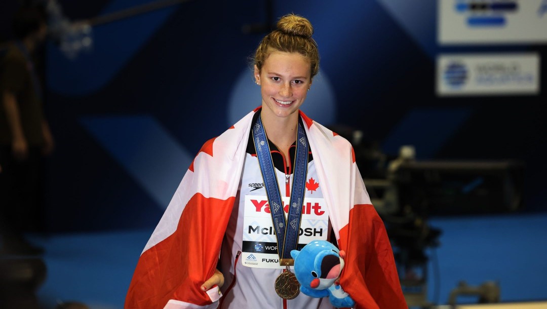 Summer McIntosh avec la médaille d'or et le drapeau canadien.