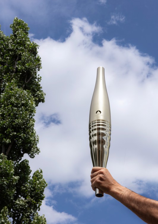 Le flambeau des Jeux olympiques de Paris 2024 présenté devant un ciel bleu.
