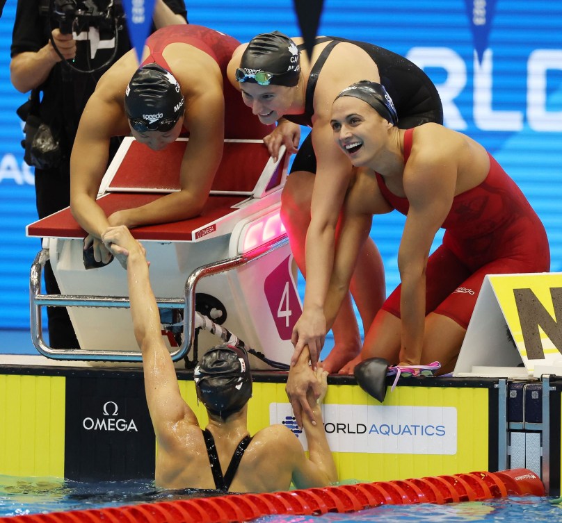 L'équipe canadienne du relais féminin 4x100 m quatre nages Kylie Masse, à droite, Sophie Angus, Maggie Mac Neil et Summer McIntosh, dans l'eau, se félicitent. 