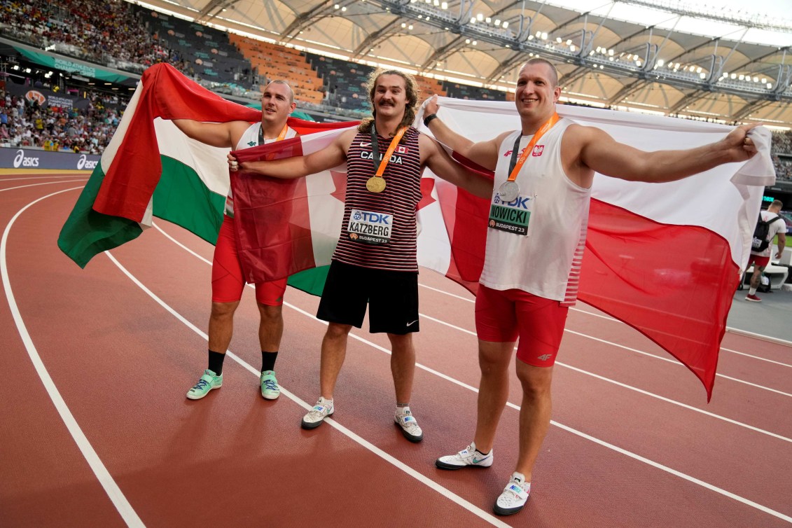 De gauche à droite, le médaillé de bronze Bence Halasz de Hongrie, le médaillé d'or Ethan Katzberg du Canada et le médaillé d'argent Wojciech Nowicki de Pologne  posent avec leur médaille et le drapeau de leur pays. 