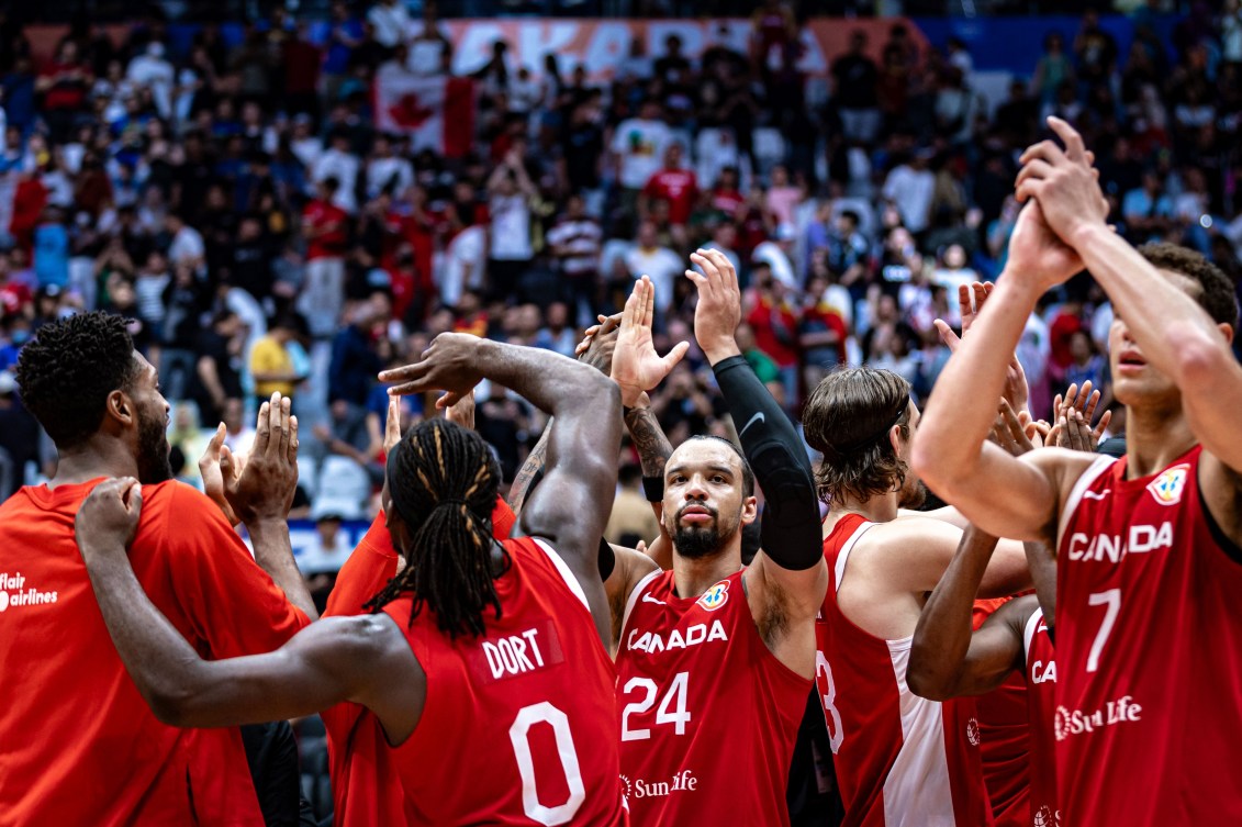 Les joueurs de basketball canadiens les mains levées. 