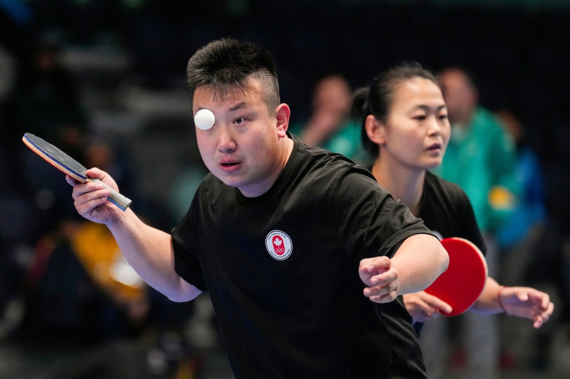 Eugene Wang, à l'avant plan, et Mo Zhang du Canada lors d'un match de tennis de table. 