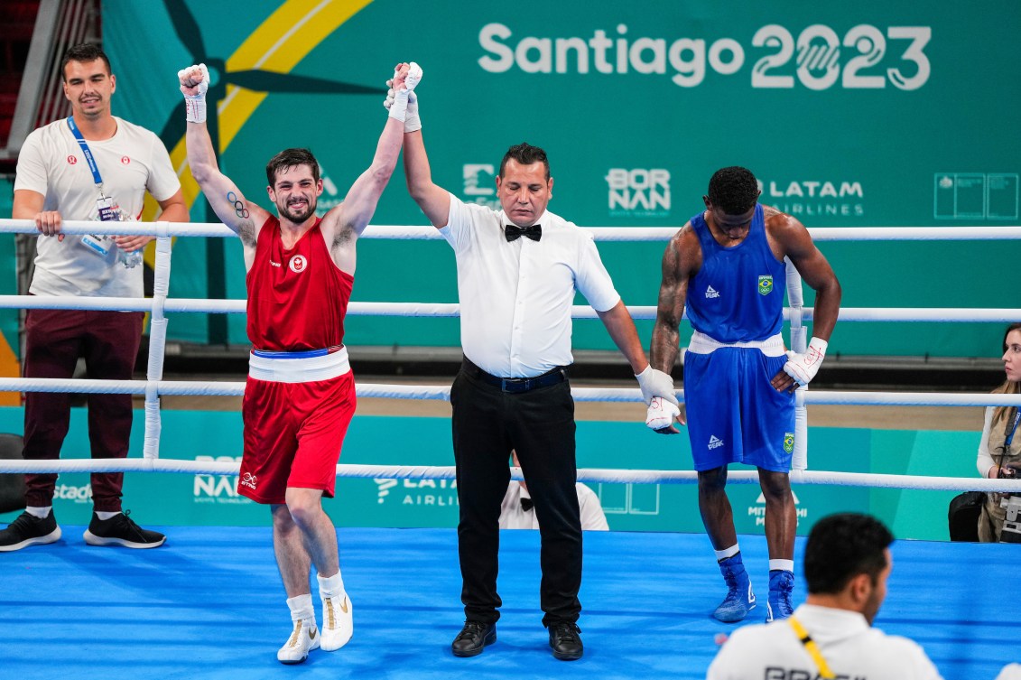 Wyatt Sanford, l'arbitre et le boxeur brésilien après le combat. Sanford lève les bras dans les airs. 