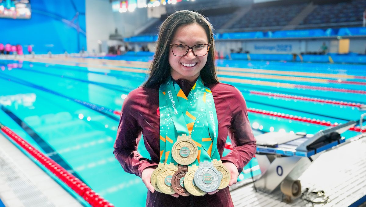 Maggie Mac Neil avec sept médailles devant la piscine. 