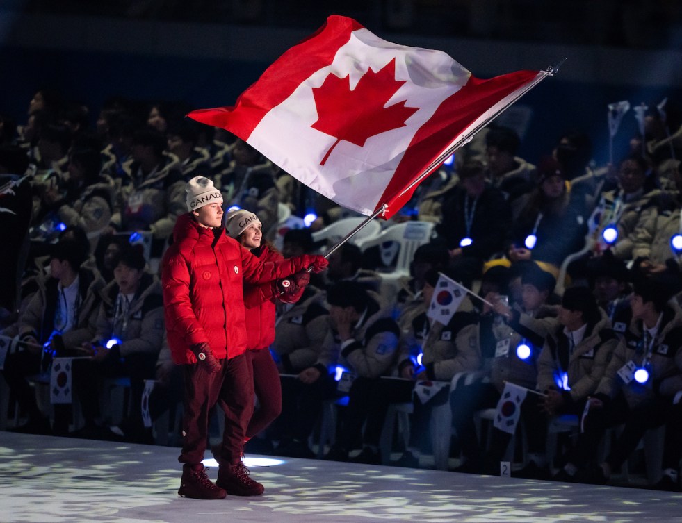 Chloe Fediuk (curling) et Charlie Beatty (ski acrobatique) portent le drapeau canadien lors de la cérémonie d'ouverture.