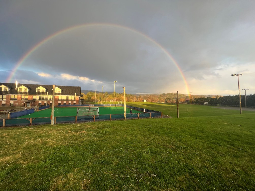 Un terrain de hockey sur gazon sous un arc-en-ciel.