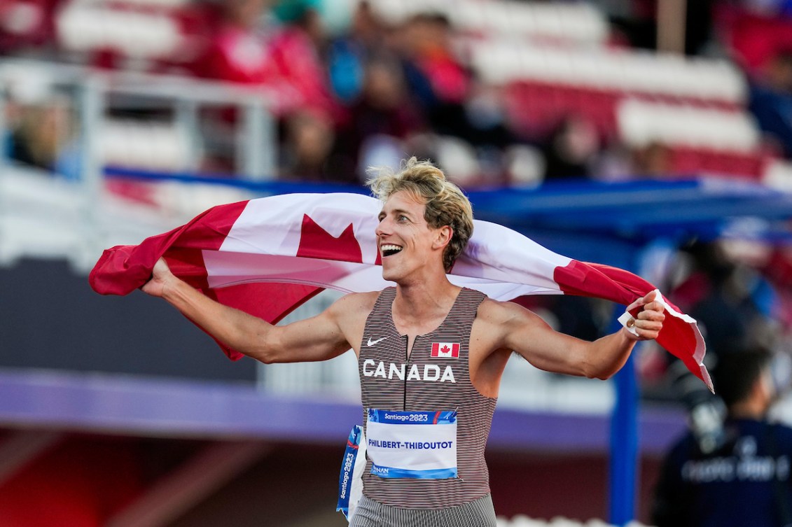 Charles Philibert-Thiboutot tient le drapeau canadien sur ses épaules. 
