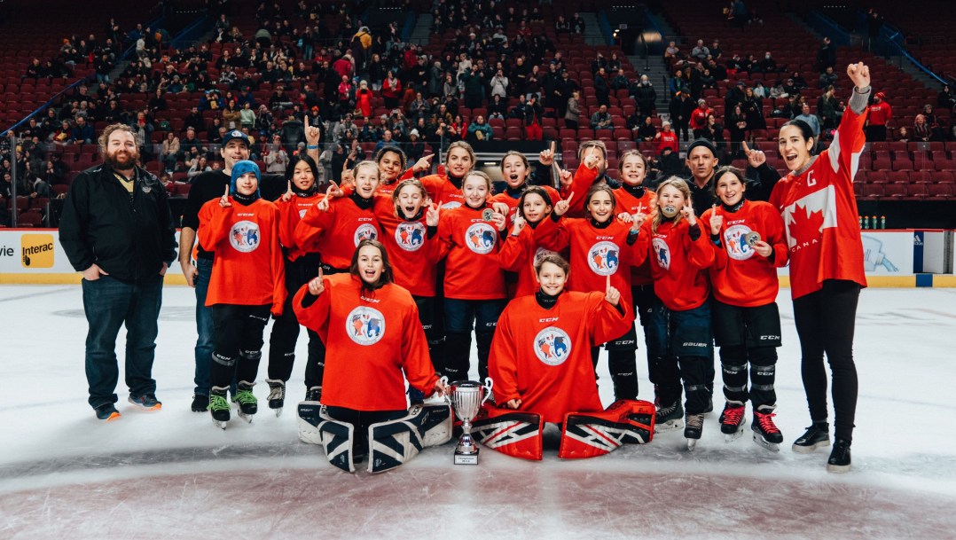 Une équipe de hockey de jeunes filles pose pour une photo.