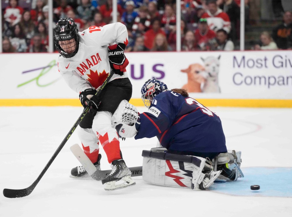 Une joueuse de hockey canadienne devant une gardienne de but américaine.