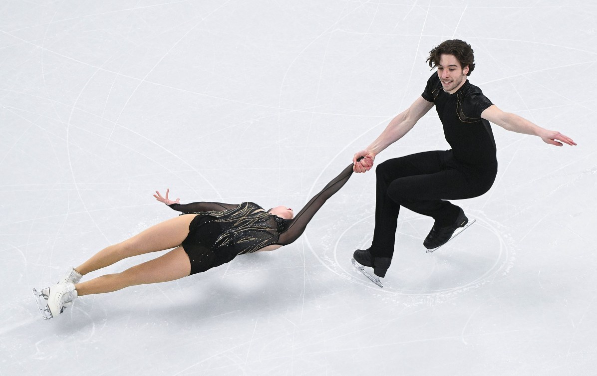 Une patineuse effectue une spirale soutenue par son partenaire. 