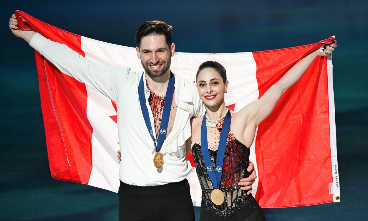 Deanna Stellato-Dudek et Maxime Deschamps devant un drapeau canadien avec leur médaille d'or au cou. 