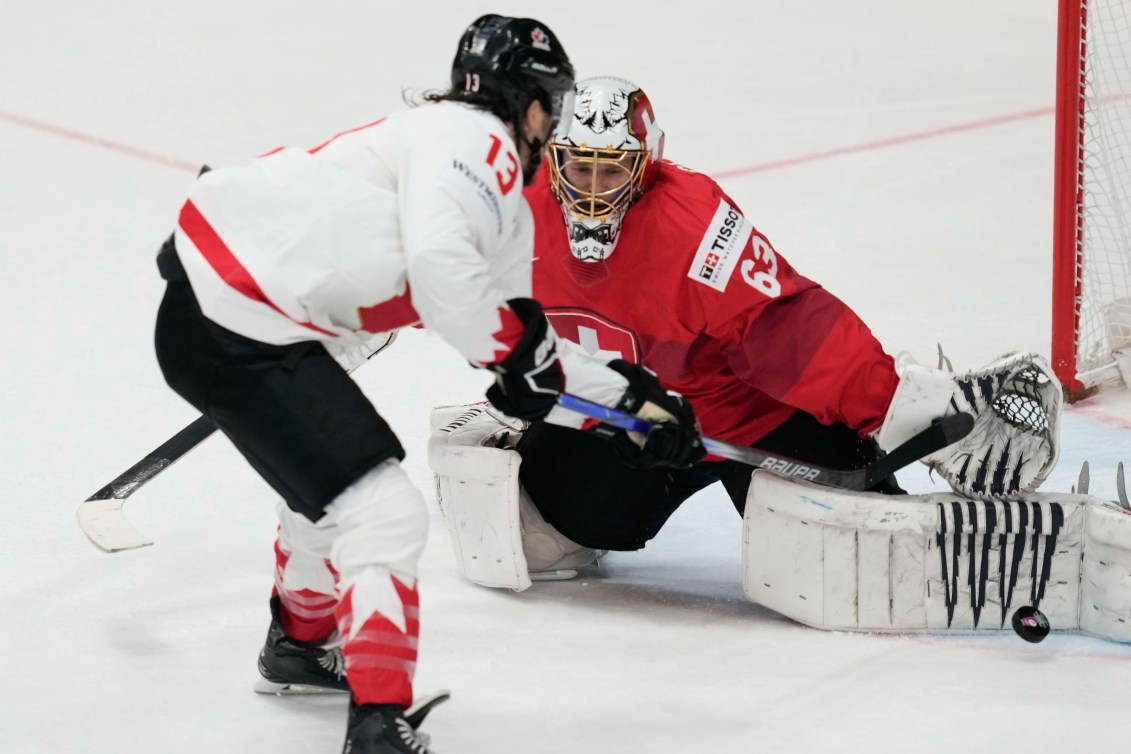 Brandon Tanev, à un contre un contre le gardien suisse, tente de soulever la rondelle du revers par dessus la jambière gauche du gardien.