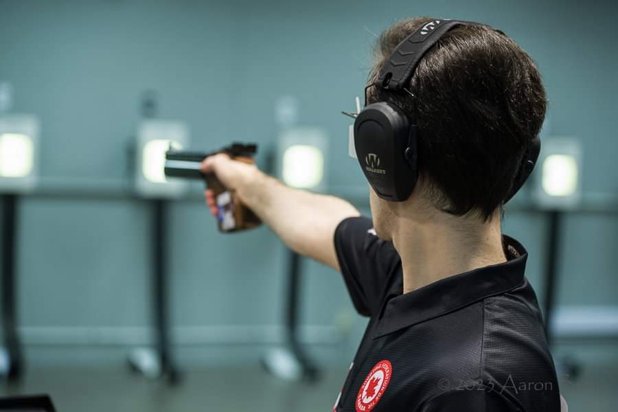 Un homme que l'on voit de dos tient un pistolet. 