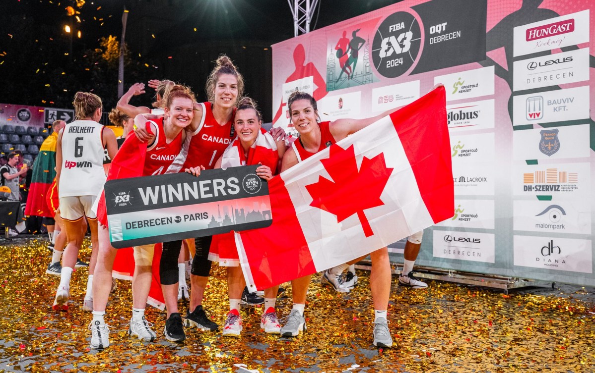 Les joueuses canadiennes posent avec une affiche Winners et un drapeau canadien.