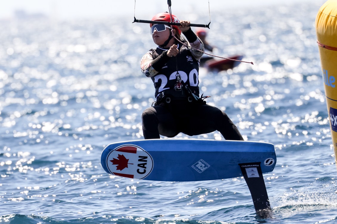 Une athlète survole l'eau sur une planche de kite. 