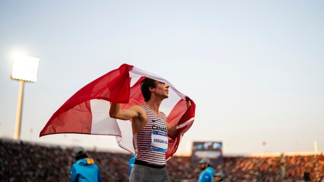 Jean-Simon Desgagnés avec le drapeau canadien sur la piste d'athlétisme.