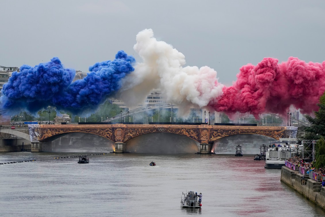 La fumée cérémonielle aux couleurs du drapeau français apparaît au-dessus de la Seine.