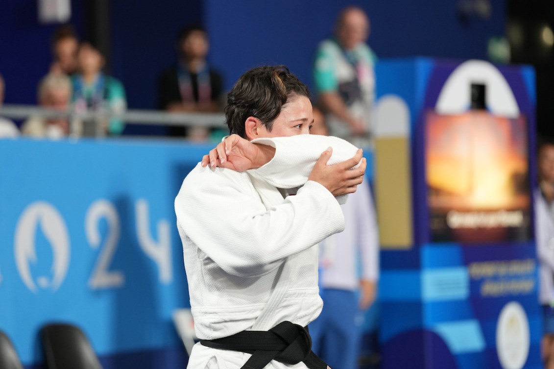 Christa Deguchi émotive le bras devant le visage. 