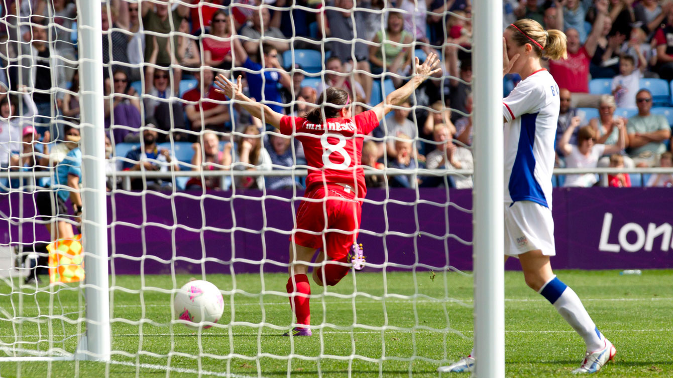 Diana Matheson de dos, aperçu à travers le filet du but de soccer. 