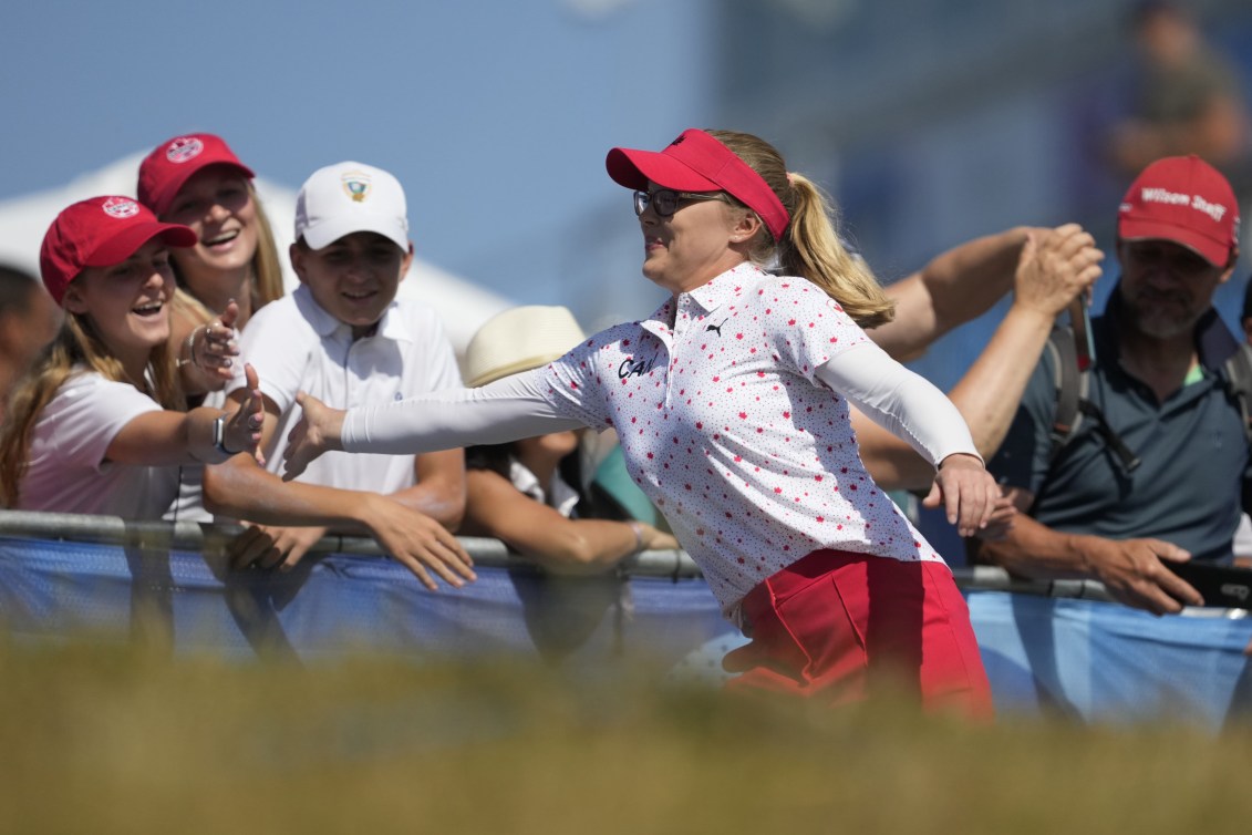 Brooke Henderson tape dans les mains des fans .