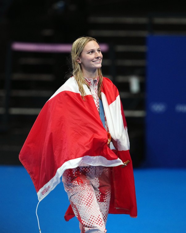 Summer McIntosh  avec le drapeau canadien sur les épaules.