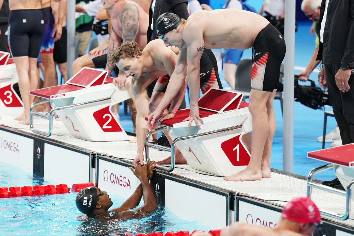 Les nageurs serrent la main de Josh Liendo, le dernier relayeur du Canada. 