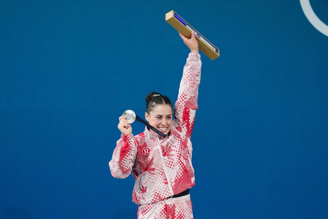 Maude Charron lève les bras avec sa médaille d'argent autour du cou.
