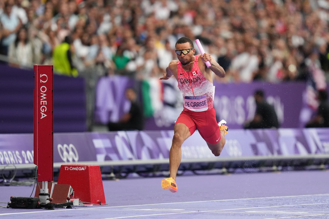 Andre De Grasse d'Équipe Canada franchit la ligne d'arrivée avec le bâton.