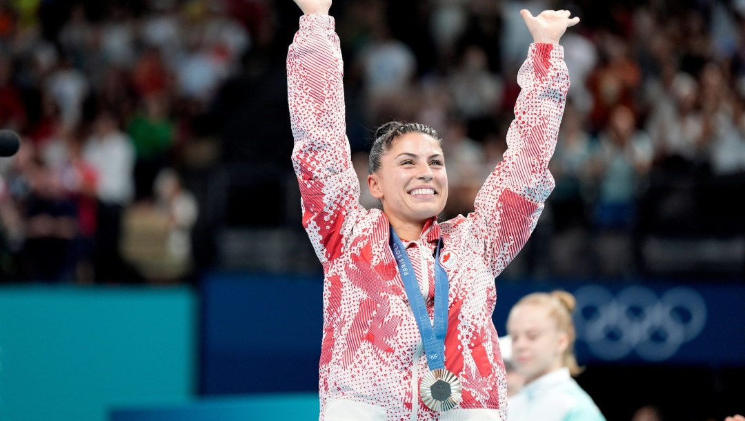 Sophiane Méthot lève les deux bras avec sa médaille de bronze autour du cou.