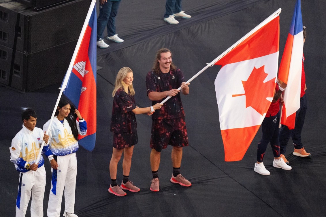 Summer McIntosh et Ethan Katzberg portent le drapeau.