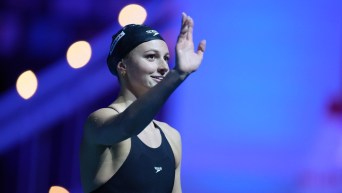 Summer McIntosh lève le bras droit dans les airs pour saluer la foule après sa médaille d'or