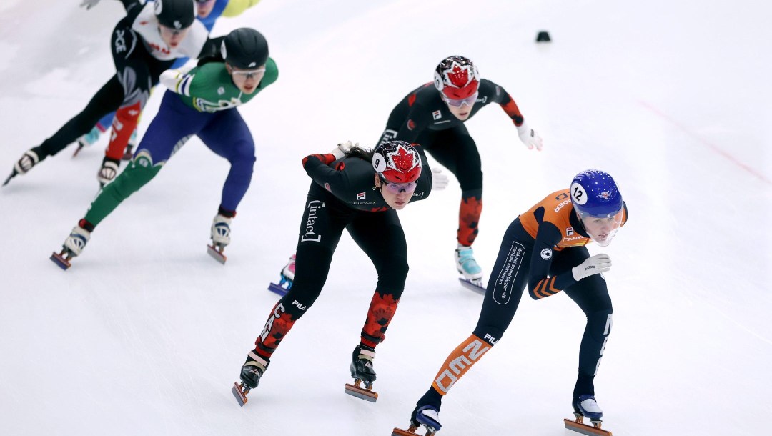 Plusieurs patineuses, dont Courtney Sarault au centre, en train de patiner autour de la piste.