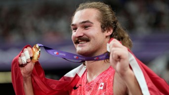 Ethan Katzberg tient sa médaille d’or, un drapeau canadien posé sur ses épaules.