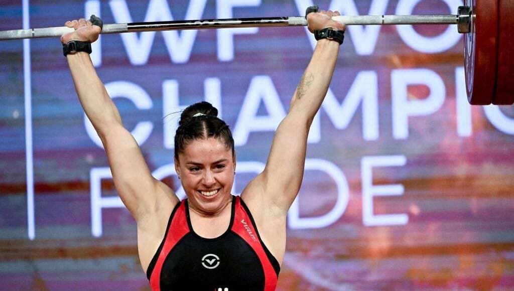 Maude Charron smiles while lifting barbell above her head