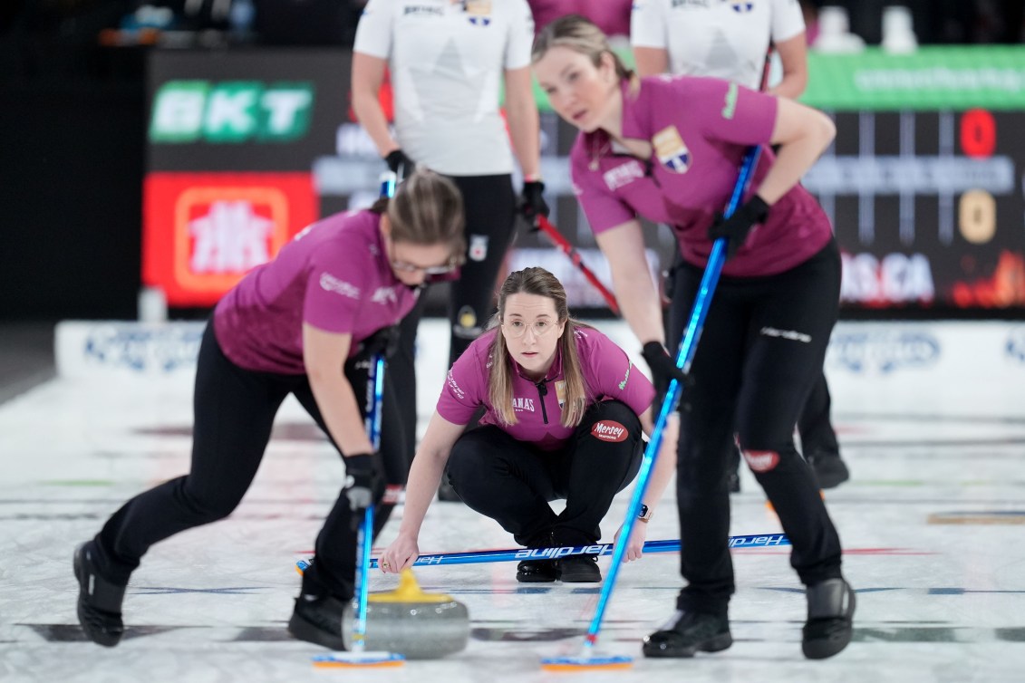 Trois joueuses de curling qui se préparent à faire un lancer.