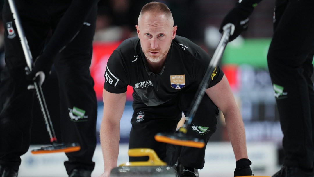 Brad Jacobs, accroupit, regarde vers l'avant alors qu'il effectue un lancer au curling.