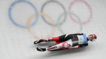 Trinity Ellis glisse devant les anneaux olympiques sur la piste de luge.